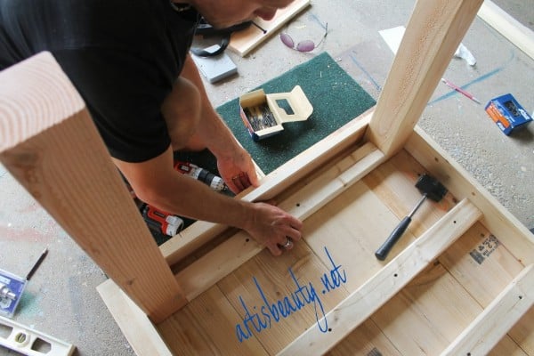 support braces between the legs of a diy farmhouse table, featured on Remodelaholic.com