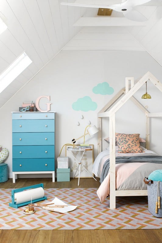 Kids room with house bed frame, blue ombre dresser, geometric rug, and cloud wall decals